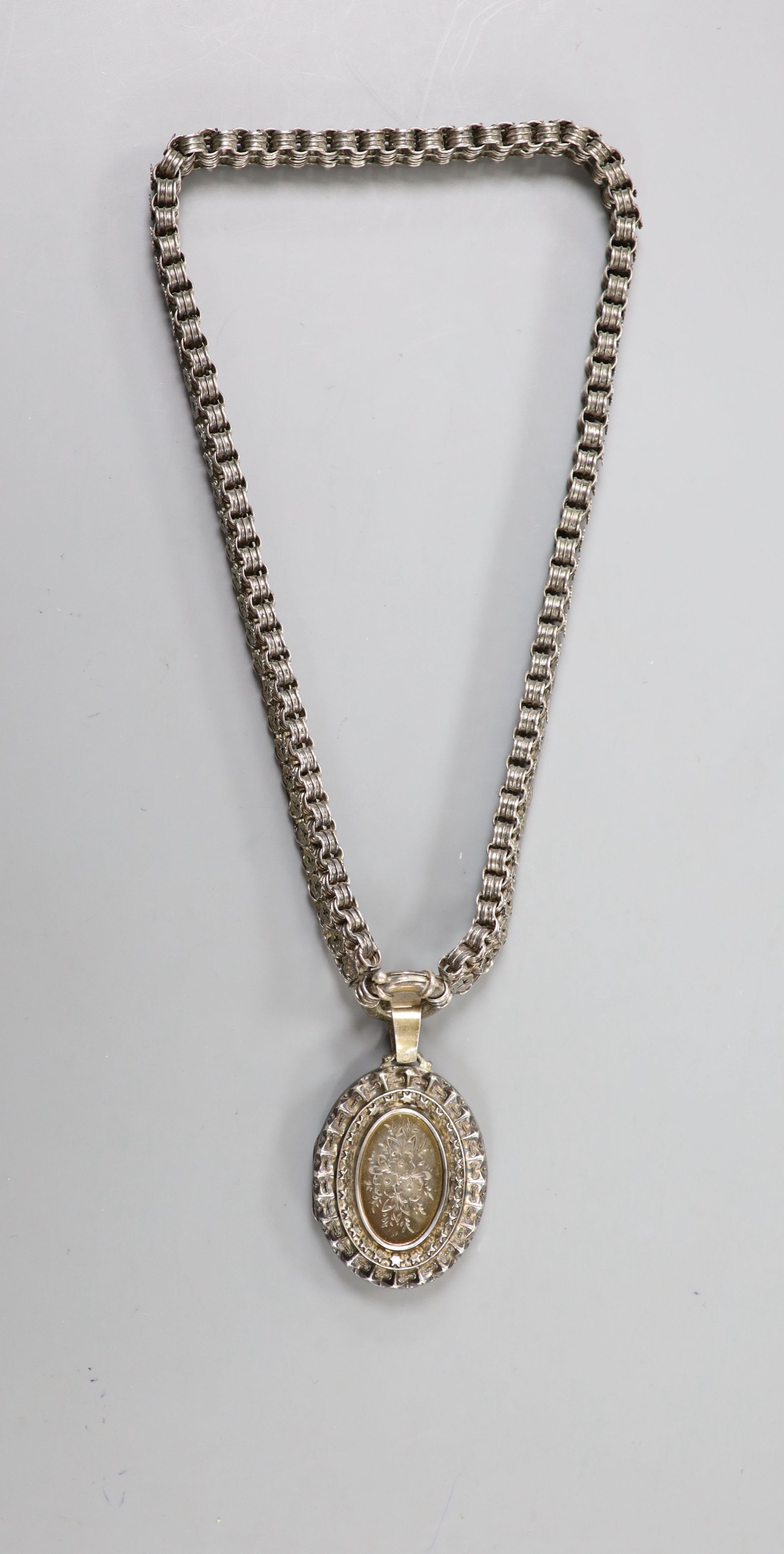 A late Victorian silver oval locket, 45mm, on a pierced white metal chain, 43cm.